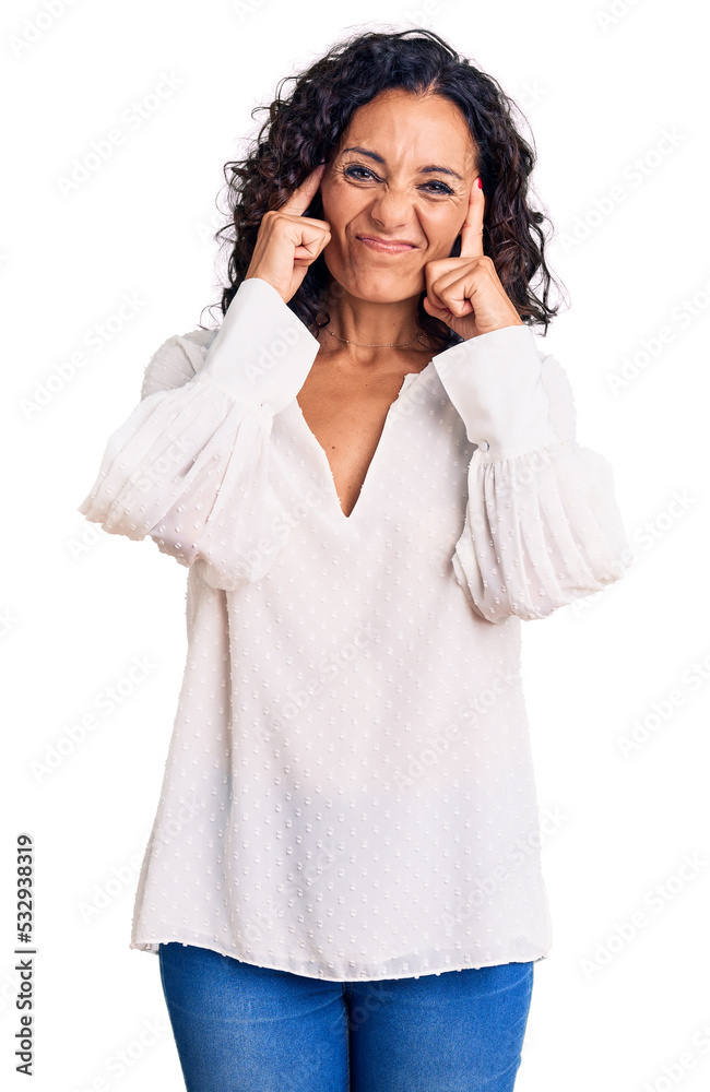 Middle age beautiful woman wearing casual sweater covering ears with fingers with annoyed expression for the noise of loud music. deaf concept. Middle age beautiful woman wearing casual sweater covering ears with fingers with annoyed expression for the noise of loud music. deaf concept.