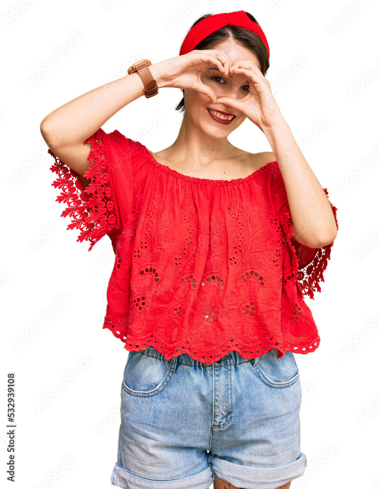 Young brunette woman with short hair wearing casual summer clothes and diadem doing heart shape with hand and fingers smiling looking through sign Young brunette woman with short hair wearing casual summer clothes and diadem doing heart shape with hand and fingers smiling looking through sign