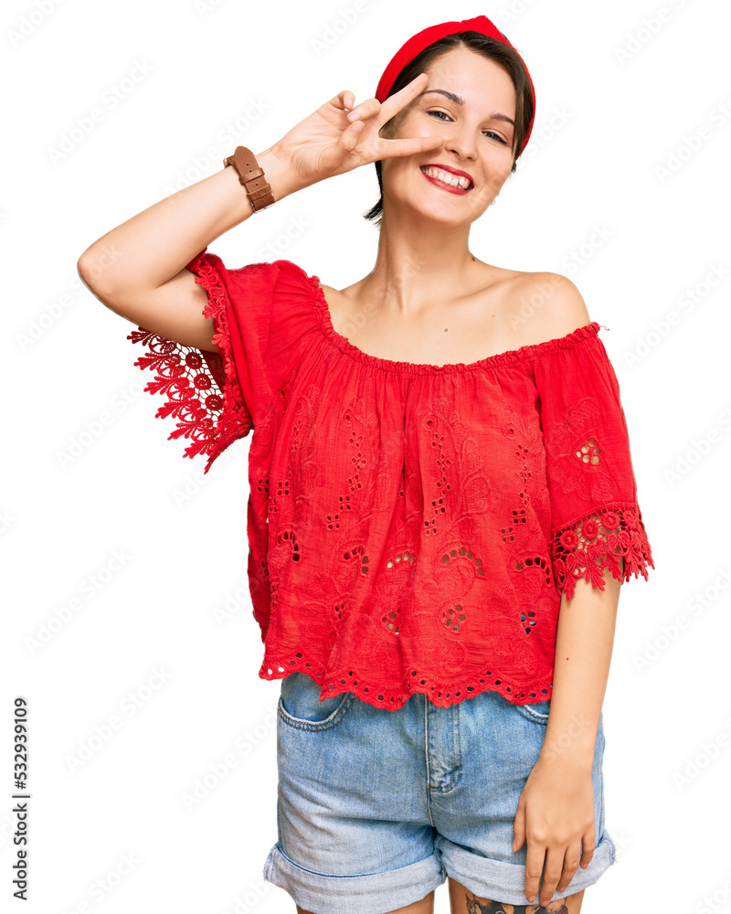 Young brunette woman with short hair wearing casual summer clothes and diadem doing peace symbol with fingers over face, smiling cheerful showing victory Young brunette woman with short hair wearing casual summer clothes and diadem doing peace symbol with fingers over face, smiling cheerful showing victory