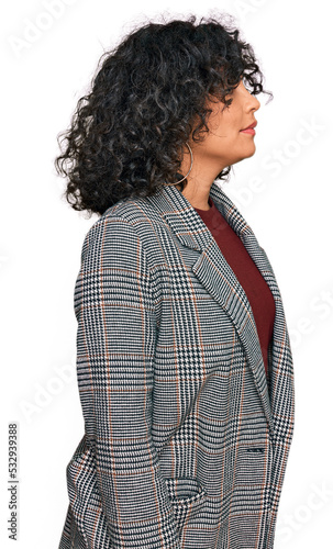 Young hispanic woman wearing business clothes looking to side, relax profile pose with natural face with confident smile.