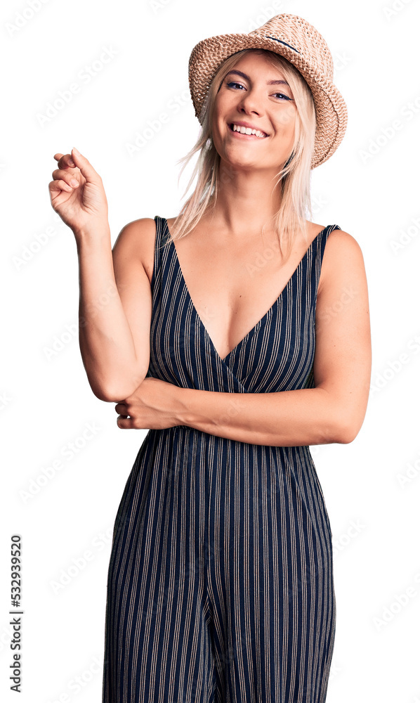 Young beautiful blonde woman wearing summer hat and dress with a big smile on face, pointing with hand and finger to the side looking at the camera. Young beautiful blonde woman wearing summer hat and dress with a big smile on face, pointing with hand and finger to the side looking at the camera.
