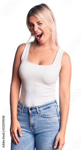 Young beautiful blonde woman wearing casual sleeveless t-shirt winking looking at the camera with sexy expression, cheerful and happy face. © Krakenimages.com