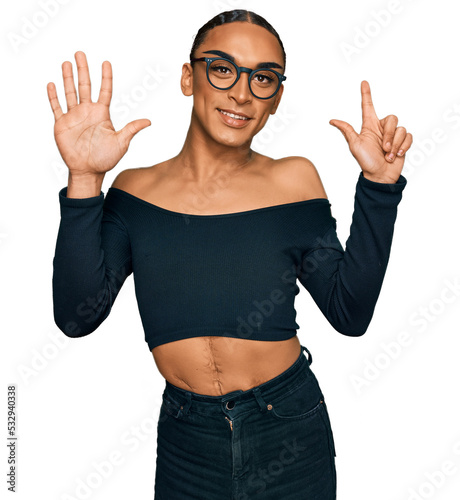 Hispanic transgender man wearing make up and long hair wearing women clothes showing and pointing up with fingers number seven while smiling confident and happy.
