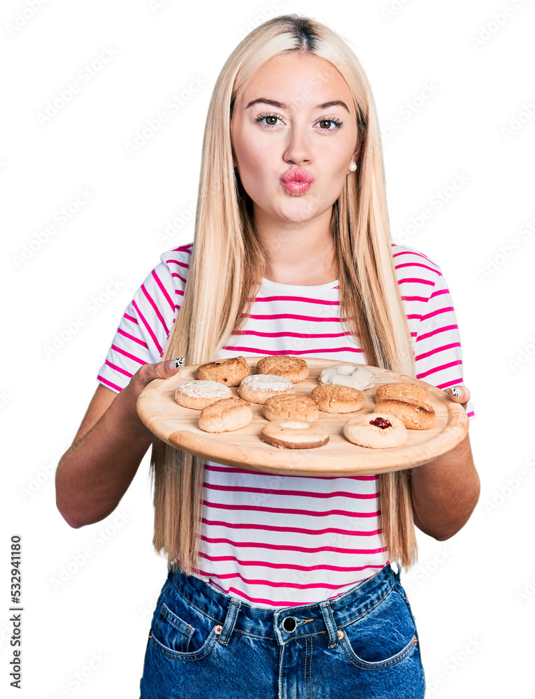 Beautiful blonde woman eating pastries looking at the camera blowing a kiss being lovely and sexy. love expression. Beautiful blonde woman eating pastries looking at the camera blowing a kiss being lovely and sexy. love expression.