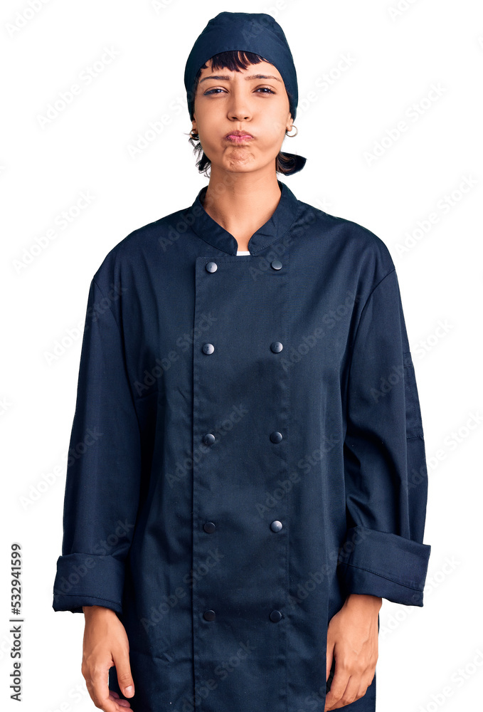 Young brunette woman with short hair wearing professional cook uniform puffing cheeks with funny face. mouth inflated with air, crazy expression. Young brunette woman with short hair wearing professional cook uniform puffing cheeks with funny face. mouth inflated with air, crazy expression.