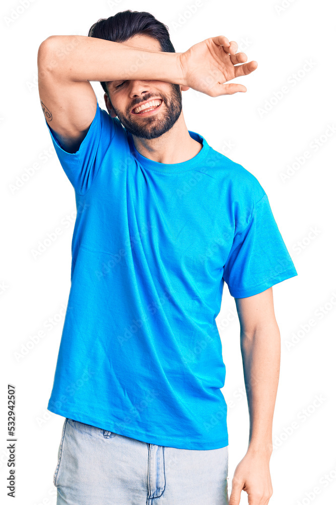 Young handsome man with beard wearing casual t-shirt covering eyes with arm smiling cheerful and funny. blind concept. Young handsome man with beard wearing casual t-shirt covering eyes with arm smiling cheerful and funny. blind concept.