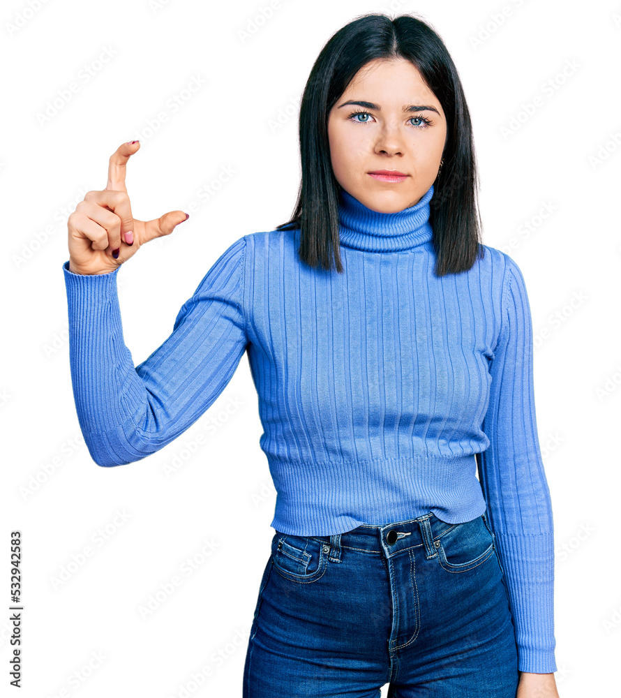 Young brunette woman with blue eyes doing size gesture holding invisible object relaxed with serious expression on face. simple and natural looking at the camera. Young brunette woman with blue eyes doing size gesture holding invisible object relaxed with serious expression on face. simple and natural looking at the camera.