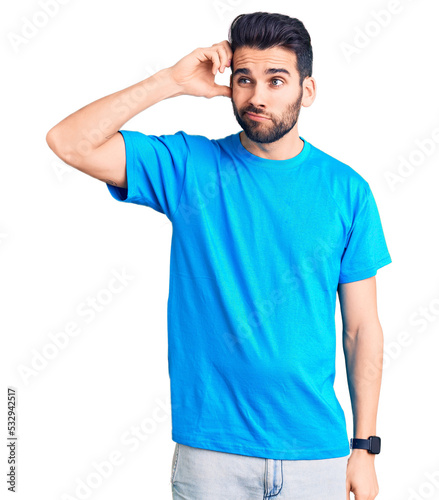 Young handsome man with beard wearing casual t-shirt confuse and wondering about question. uncertain with doubt, thinking with hand on head. pensive concept.