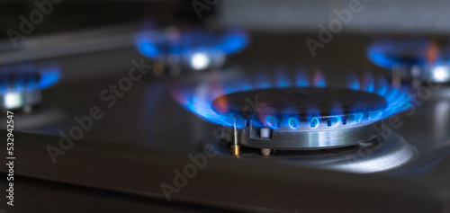Close-up of a blue fire from a kitchen stove. 4 gas burners with a burning flame. economy concept. wide banner