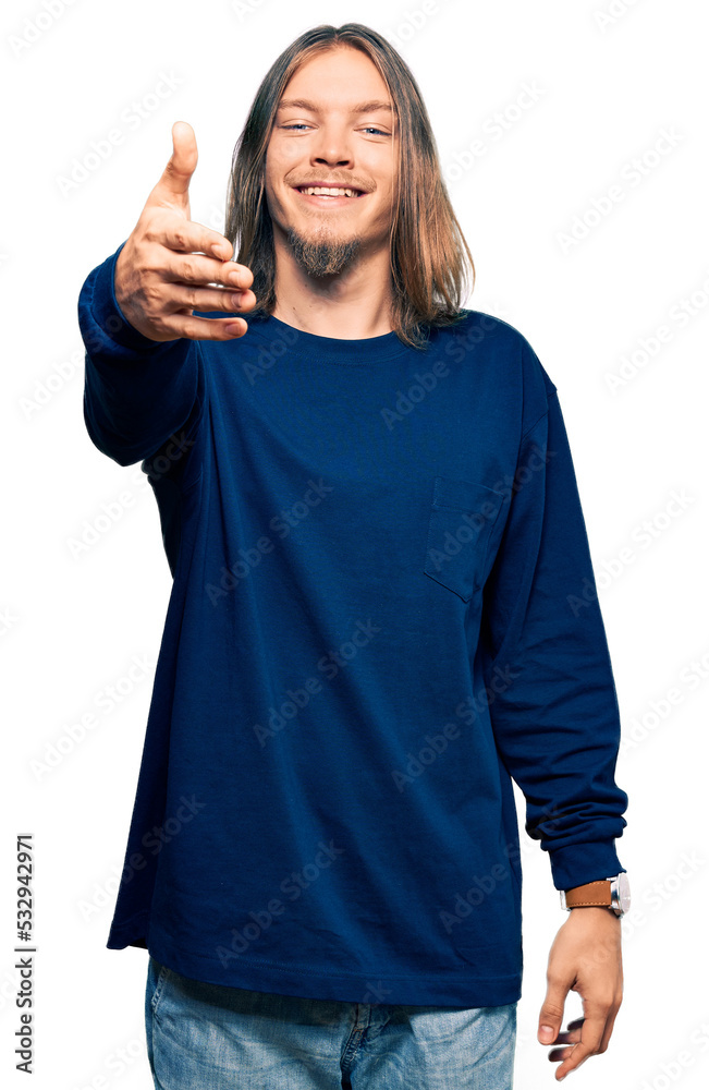 Handsome caucasian man with long hair wearing casual winter sweater smiling friendly offering handshake as greeting and welcoming. successful business. Handsome caucasian man with long hair wearing casual winter sweater smiling friendly offering handshake as greeting and welcoming. successful business.