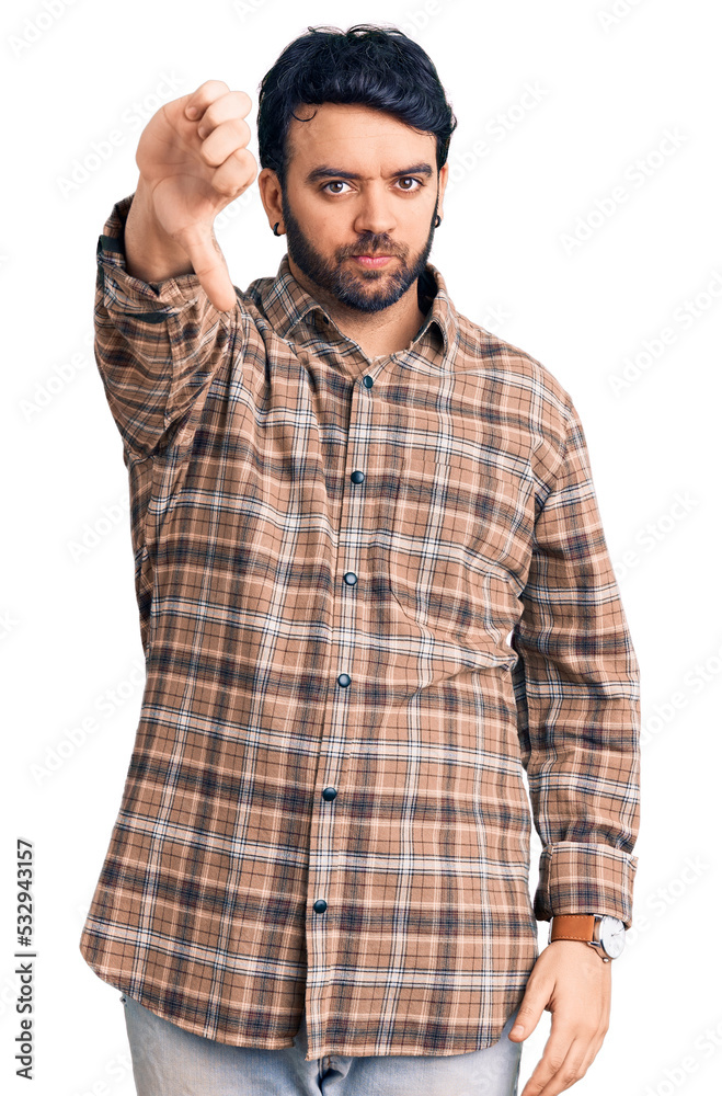 Young hispanic man wearing casual clothes looking unhappy and angry showing rejection and negative with thumbs down gesture. bad expression. Young hispanic man wearing casual clothes looking unhappy and angry showing rejection and negative with thumbs down gesture. bad expression.