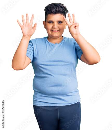 Little boy kid wearing sports workout clothes showing and pointing up with fingers number eight while smiling confident and happy.