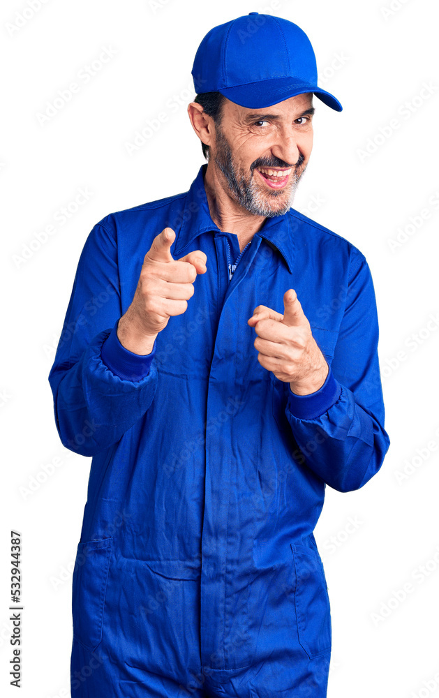 Middle age handsome man wearing mechanic uniform pointing fingers to camera with happy and funny face. good energy and vibes.