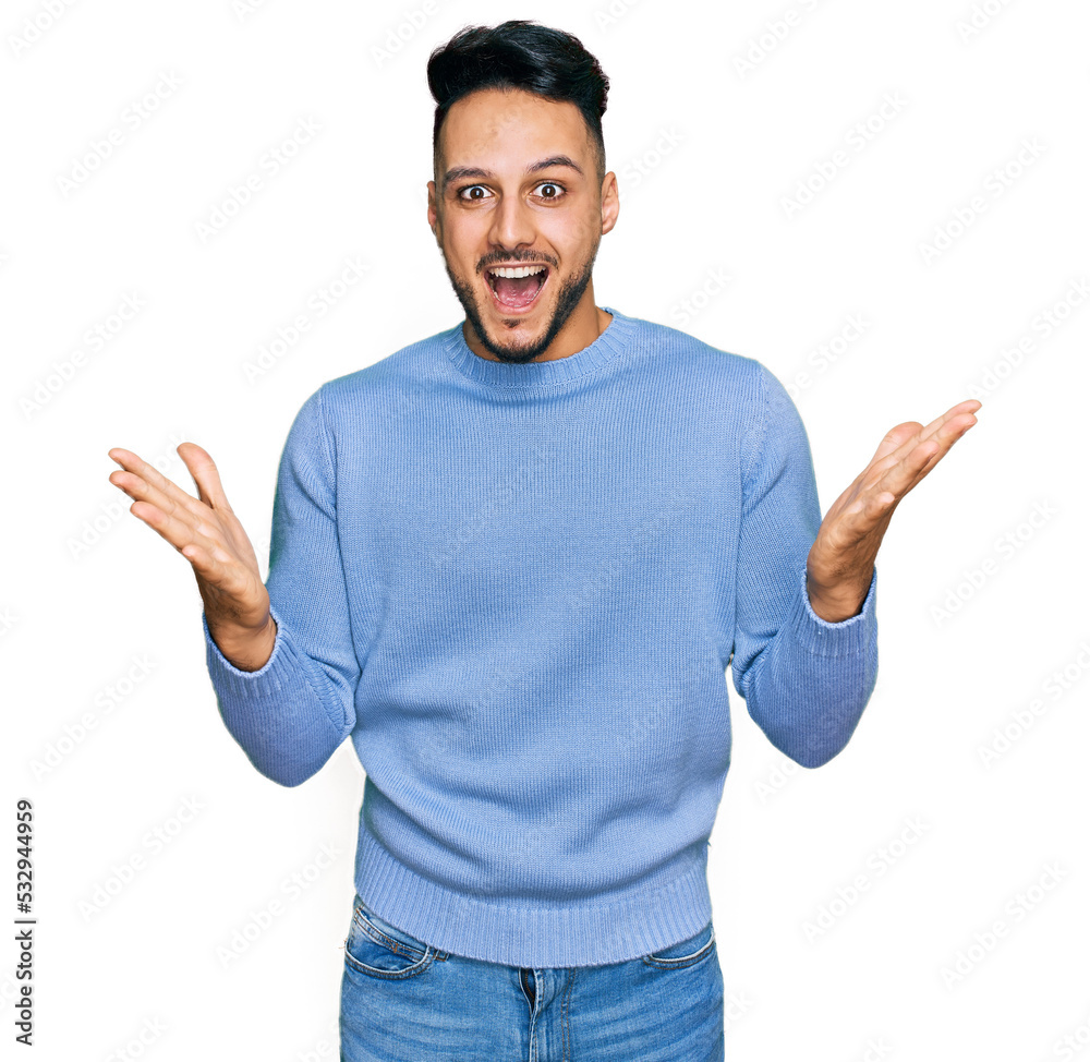 Fototapeta premium Young arab man wearing casual clothes celebrating victory with happy smile and winner expression with raised hands