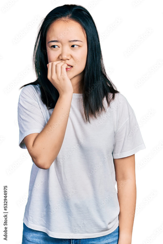 Young chinese woman wearing casual white t shirt looking stressed and nervous with hands on mouth biting nails. anxiety problem. Young chinese woman wearing casual white t shirt looking stressed and nervous with hands on mouth biting nails. anxiety problem.