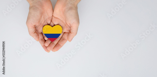 The national flag of Colombia of arms in female hands. Flat lay, copy space.