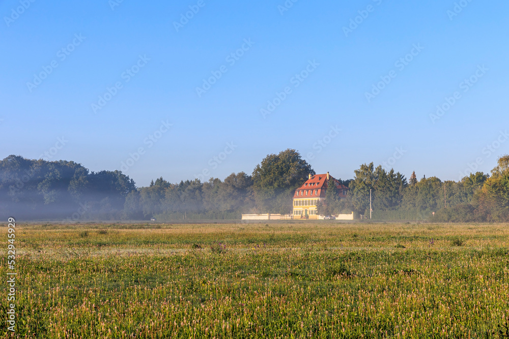 Fototapeta premium Clouds of fog on a sunny morning over the meadows in Siebenbrunn near Augsburg