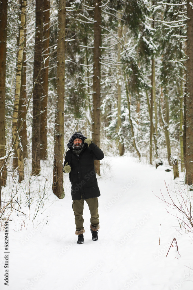 Naklejka premium Bearded man in the winter woods. Attractive happy young man with beard walk in the park.