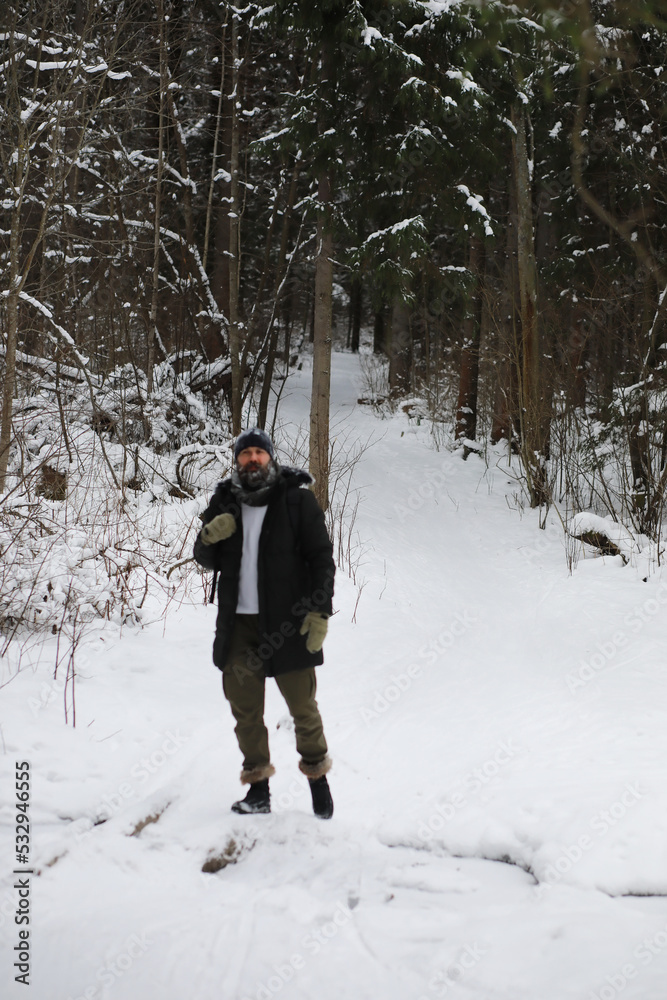 Bearded man in the winter woods. Attractive happy young man with beard walk in the park.