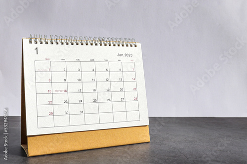 January 2023 Desktop calendar for planners and reminders on a wooden table on a white background.