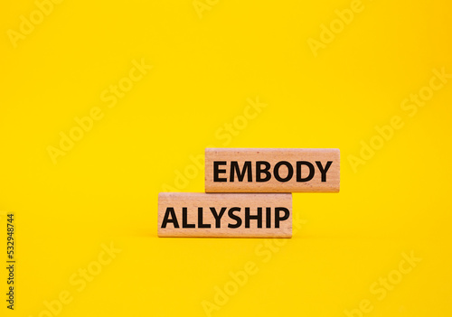 Embody Allyship symbol. Concept word Embody Allyship on wooden blocks. Beautiful yellow background. Business and Embody Allyship concept. Copy space