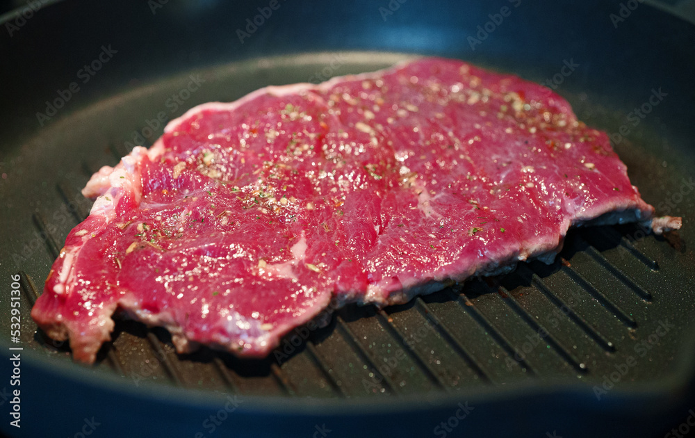 Bloody beef entrecote is fried in a pan.