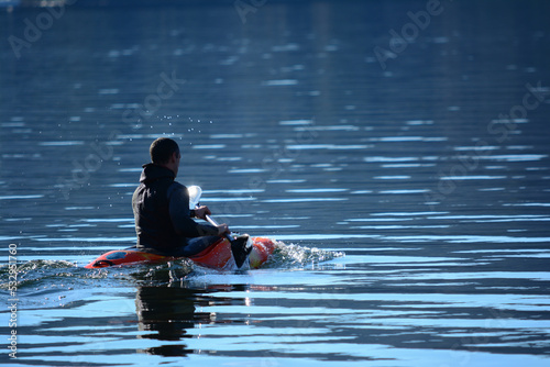 young man in a small acrobatic kayak in the morning on a lake