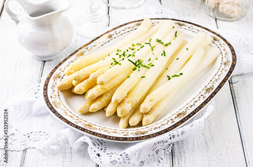 Traditional style steamed white asparagus with sauce hollandaise served as close-up on a classic design plate