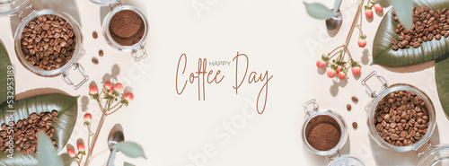 Coffee Day holiday banner with organic roasted coffee beans on a green leaves and coffee powder in a glass jar on an ivory background with shadows and congratulation inscription. Flat lay, Banner size