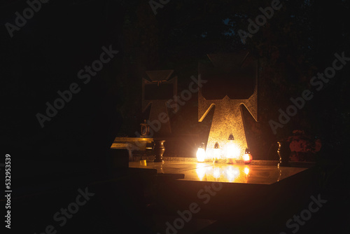 warm lamp light near tomb stone on cemetery at night, soft focus concept photography