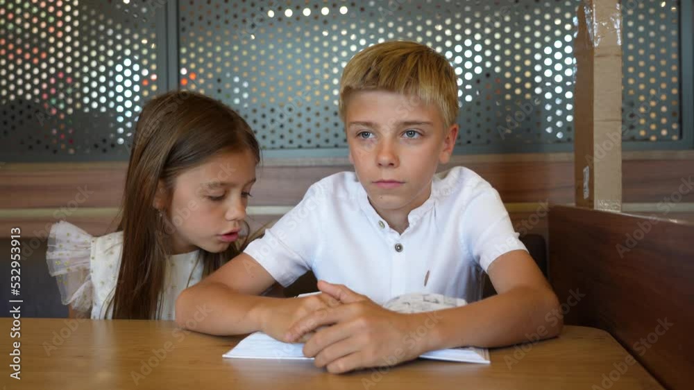 Caucasian boy and girl relaxing with cartoon book, cute siblings sitting enjoy reading book at cafe while waiting for their order. Caucasian boy and girl relaxing with cartoon book, cute siblings sitting enjoy reading book at cafe while waiting for their order.