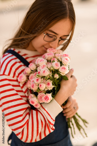 Close-up view of bouquet of light pink roses flowers which woman tenderly holding and hug