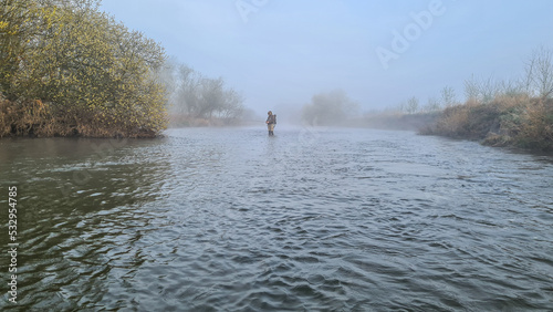 person walking on the river/ fly fishing