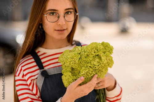 portrait of beautiful young woman holding bouquet of fresh light green carnation in her hands