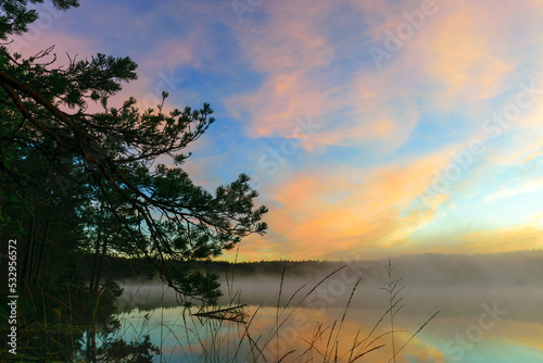sunrise picture with gorgeous sky, fog covers the surface of the lake, sunrise colored sky