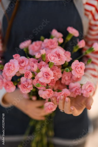 selective focus of bunch of small pink carnation flowers in woman hands. Close-up