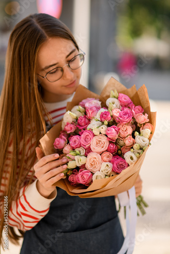 young woman tenderly holding bouquet of pink rose flowers in wrapping paper