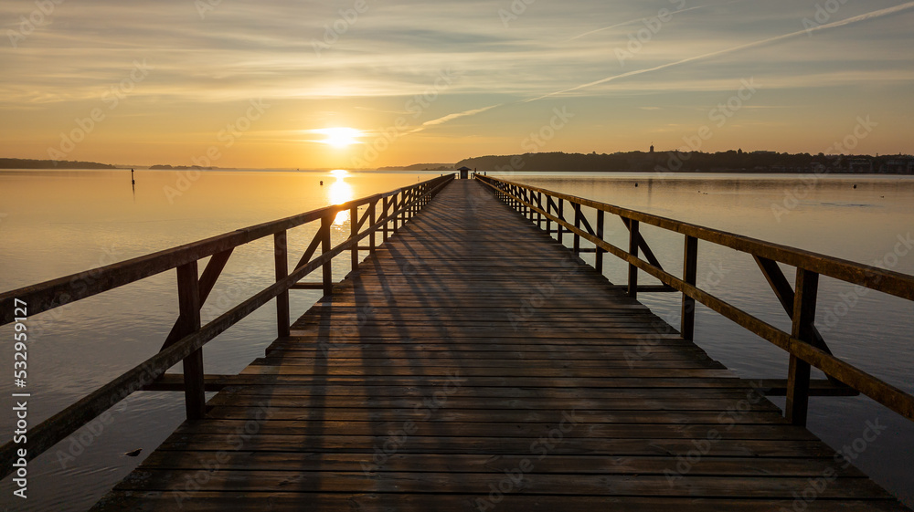 Wooden walkway in the foreground. Middle ground the Baltic Sea. Clear sky at sunset. Harrislee, Flensburg, Fjord, Germany