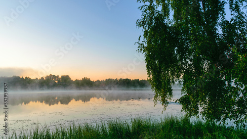 autumn morning by the lake, fog over the surface of the water, a moment before sunrise