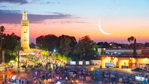 The Jema el Fna square in the background Koutoubia Mosque minaret at medina quarter at dusk with crescent moon - Marrakesh, Morocco