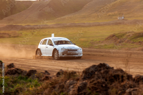 Rally off-road car make a turn with the clouds and splashes of sand, gravel and dust during rally championship