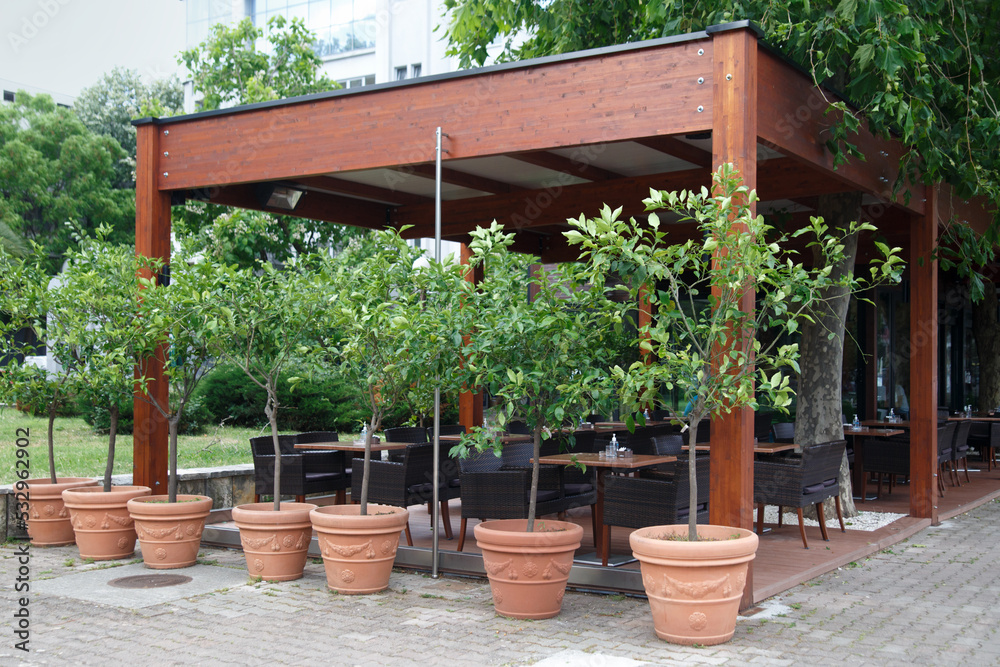 A cafe under a canopy and potted trees outside.