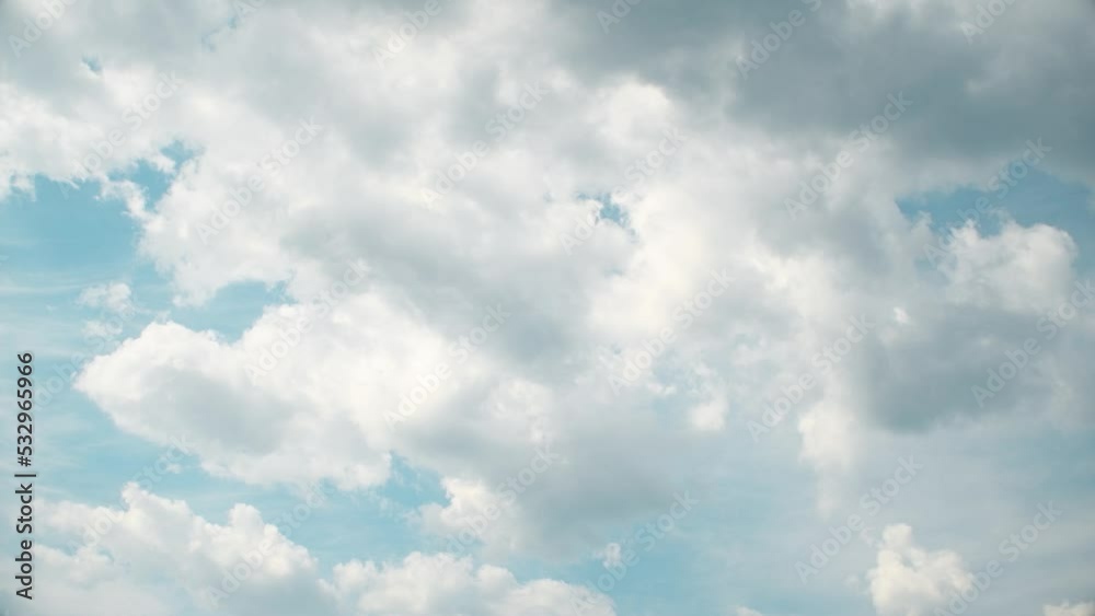 Slowly moving cumulus clouds against a blue sky. Calm, peaceful landscape in summer weather. White fluffy clouds.