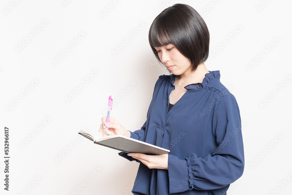 ノートにメモを書いている若い女性 ノートにメモを書いている若い女性