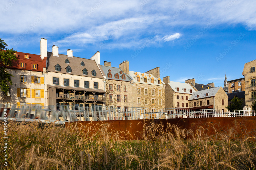 Historic buildings on Place de Paris in the Petit-Champlain sector seen during a fall golden hour morning with decorative grasses in the foreground, Quebec City, Quebec, Canada