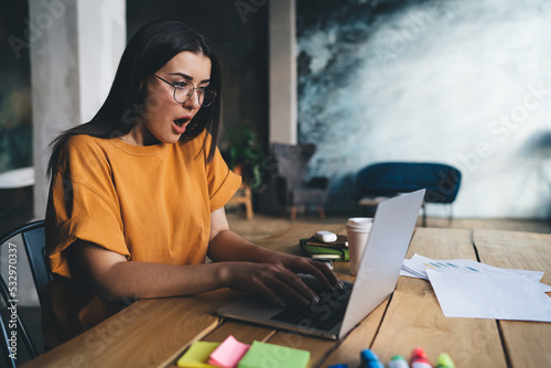 Surprised woman using laptop sitting at desk