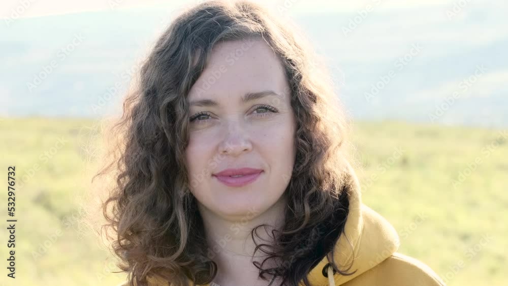 Portrait of curly happy woman outdoors. Closeup young female person in yellow field in sunny day. Female turned her head with curly hairs. Portrait of curly happy woman outdoors. Closeup young female person in yellow field in sunny day. Female turned her head with curly hairs.