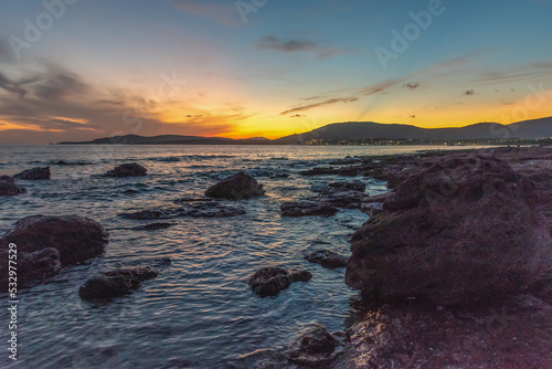 Colorful sky over Alghero rocky shore at sunset