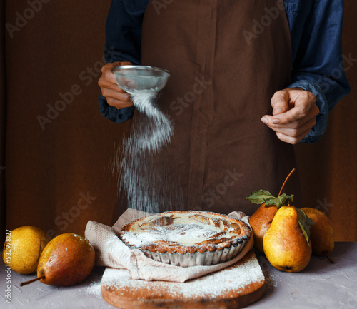 Photography A woman sprinkling a freshly baked cake with powdered sugar, close-up