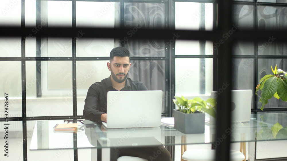Fototapeta premium Businessman with glasses in the office working on a laptop